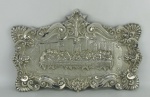 Santa Ceia - Placa decorada ao estilo D. João V, em metal espessurado a prata, com trabalhos em conchas, flores e volutas. Med. 29x44,5 cm.