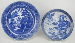 Dois pratos decorativos, sendo um antiga porcelana oriental, tendo ao centro paisagem lacustre, nos tons de azul e com marca da manufatura no verso e o outro em porcelana inglesa, com decoração pombinhos na cor azul. Diams. 21 e 26 cm.
