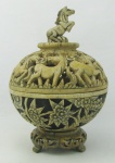 Incensório com peanha em pedra natural, decorado com flores e folhagens em relevo. Tampa trabalhada com cavalos e detalhes vasados. Alt. com peanha 17 cm.