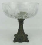 Centro de mesa de pé alto, em cristal translúcido, lapidado com sulcos e base em bronze trabalhado com flores, folhas e bambus em relevo. Med. 22x21cm.