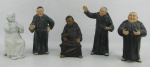 Cinco estatuetas em pasta dura representando "Frades", sendo 4 policromadas e uma branca. Três policromadas apresentam numeração a crivo e a branca localizada Germany e numerada, tendo esta pescoço colado. Uma estatueta policromada com desgastes na policromia. Al. maior e menor 16 e 12,5cm.