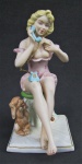 Grupo escultórico em biscuit policromado, representando "Jovem semi desnuda com seu cão. Alt. 21,5cm.