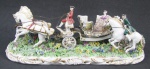 Grupo Escultórico em porcelana italiana policromada, com marca da manufatura e localizada Italy na base, representando "Carruagem". Detalhes em dourado. Com restauros e pequenas perdas. Med. 12x36x12cm.