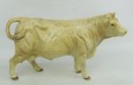 Estatueta em porcelana européia em tons de creme, representando "Vaca". Med. 11x20x5,5cm.