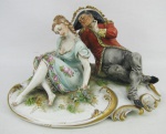 Grupo escultórico em porcelana européia, policromada, com marca da manufatura na borda da base, representando "Cena de galanteio". Detalhes em dourado. Com pequeno restauro. Med. 14x24x18cm.