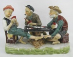 Grupo escultórico em biscuit policromado representando "Jogo de cartas". Med. 17,5x26x13,5cm.