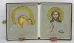 Dois ícones em metal prateado e dourado, representando "Nossa Senhora com Menino e Jesus Cristo". Acondicionados a caixa original forrada em courino marrom. Med. de cada ícone 13x10,5 e Med. caixa aberta 14x24,5cm.