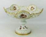 Meissen - Centro de mesa em porcelana alemã, com marca da manufatura na base, decorada com pintura floral em policromia, dourado, vazados e trabalhos em relevo. Med. 16,5x22,5cm.