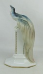 Bela estatueta art-deco, de coleção em porcelana alemã, marca da manufatura Fraureuth, policromada, representando "Pássaro sobre coluna. Detalhes em dourado. Alt. 27cm.