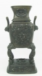 Floreira oriental em bronze patinado e decorado em relevo com dragões, folhagens e cabeças de cães fó. Pernas altas e recurvas. Falta um adereço na base. Alt. 24cm.