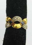 Anel em ouro 18k, amarelo e branco, com pedra central na cor preta e diamantes. Aro 14. Peso 8.2g. Este ítem não se encontra no local do leilão.