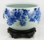 Cachepot em porcelana, oriental com decoração de folhagens no tom azul. Acompanha base em madeira. Med. 21,5x35cm.