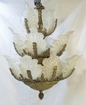 Belo lustre para 17 luzes com 3 estágios em metal dourado e folhas em vidro de murano. Uma das folhas colada. Med. 66x62cm.