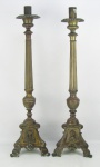 Dois antigos tocheiros em bronze, decorados com trabalhos de gomos e sulcos. Bases triangulares com folhagens, volutas, perolados e tendo em cada face busto de figura sacra em relevo. Alts. 83,5 e 82,5cm.