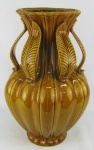 Grande vaso em cerâmica porcelanizada no tom caramelo, decorado com folhagens em alto relevo. Base marcada "Vaso Nora". Borda com pequeno lascado. Alt. 45cm.