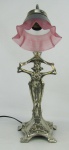 Luminária de mesa art-noveau em metal espessurado a prata, na forma de figura feminina. Cúpula em vidro foscado, com trabalhos de frisos no tom rosa e em relevo. Alt. 46cm.