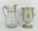 Duas peças, sendo taça em alpaca espessurado a prata, decorada com trabalhos em baixo relevo e apliques de pedras coloridas e jarra em cristal lapidado com sulcos e friso, com alça e borda  em metal. Alts. 15,5 e 19cm.
