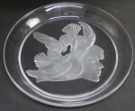 Luciana Roselli - Prato em cristal translúcido decorado com lapidações em satiné de rosto feminino com cabelos na forma de pássaros. Assinado no verso. Diam. 32cm.