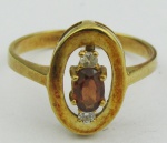 Anel em ouro 18k, com 2 brilhantes e pedra vermelha. Aro 17. Peso 3.7g. Este ítem não se encontra no local do leilão.