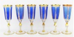 Seis belos e raros flutes em cristal tcheco, no tom azul e translucido, com lapidações de sulcos e facetados. Ricamente decorados com detalhes em dourado. Alts. 20cm.
