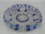 Cinzeiro em cristal tcheco, no tom azul e translúcida, decorado com lapidações de sulcos, bico de jaca, tijolinho, rosetas e estrelas. Med. 3,5x19cm.