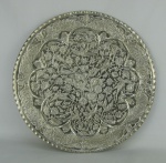 Medalhão em metal espessurado a prata, profusamente decorado com flores, folhagens e pássaros em relevo. Diam. 39cm.