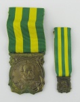 Duas comendas em metal dourado, contendo no verso as inscrições "A Marinha brasileira ao seu glorioso patrono 1957" e no anverso o busto de Almirante Tamandaré em relevo. Compts. 4 e 1,5cm.