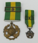 Duas comendas em metal dourado, obtidas por condecoração de tempo de serviço, 10 anos, na forma de brasão da república, contendo no verso as inscrições "Decreto de 15 de Novembro de 1901". Compts. 3,5 e 2cm.