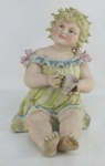 Estatueta em biscuit europeu, policromado, representando "Menina sentada com xícara". Um pé colado. Med. 29,5x19x23cm.