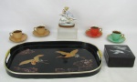 a) Seis peças, sendo caixa e bandeja em laca tendo a bandeja decoração com pintura de paisagem com pássaros e a caixa de pássaros em madreperola, e 4 xícaras em porcelana, sendo uma de cada cor. Med. bandeja 2,5x42x27cm. b) Belo grupo escultórico em porcelana européia, policromada, representando 'Meninas". Base em madeira. Med. total 12x9x5,5cm.
