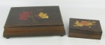 Duas caixas retangulares, em madeira, decoradas com trabalhos de flores e folhagens em marqueterie. Pequenas marcas de uso. Meds. 6,5x26,5x19 e 5x14x9cm.