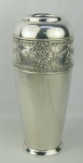 Vaso em metal prateado, decorado com trabalhos de guirlanda com flores, folhagens e laços de fita em relevo. Base apresenta marca e numeração. Base soldada e com pequenas mossas. Alt. 31cm.