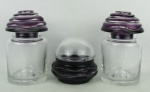 Três potes em cristal tcheco, Bohemia, um ainda apresenta a etiqueta original da manufatura, nos tons translúcido e lilás, sendo em 2 potes o cristal lilás a tampa e em um a base, com lapidações em frisos bisotados curvos e texturas. Os 2 potes maiores apresentam discretos bicados e lascadinhos de uso na base das tampas e na borda dos potes. Alts. 17,5, 17 e 11cm.