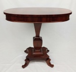 Elegante mesa de apoio em madeira, tampo oval sobre coluna de seção quadrada apoiada em platô inferior terminando em 4 pés recurvos. Med. 67x75x55,5