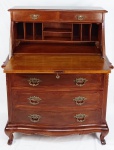 Bureau Writing Desk em madeira entalhada, formada por 3 gavetões, encimados por tampo de abrir com escaninhos no interior. Parte superior com 2 gavetinhas. Puxadores e espelho da fechadura em bronze cinzelado. Pés com volutas. Med. 119,5x93x52,5cm (fechada).