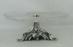Centro de mesa em cristal lapidado em rosetas, estrelas, folhas e sulcos bisotados. Borda serrilhada. Base em metal espessurado a prata com trabalhos de parreiras e cachos de uva. Med. 12,5x32cm.