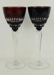 Par de taças em cristal europeu, na tonalidade doublet rubi e translúcido, lapidadas em sulcos bisotados e facetados. Haste sextavadas e serrilhadas. Alts. 22cm.