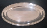 WOLFF - Travessa oval em metal espessurado a prata, com detalhes em alto relevo na borda modelo croisé. Apresenta detalhes devido ao tempo de uso. Medidas 52 x 36 cm.