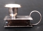 Porta vela em metal espessurado a prata com alça suporte para caixa de fósforo. Medida altura 5 cm e comprimento com alça 8,5 cm.