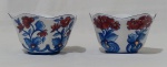 Par de bowls em porcelana na tonalidade branca com pintura de flores nas tonalidades azul e vermelho. Medida altura 6 cm e largura 10 cm.