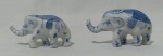 Par de bibelôs em porcelana representando elefantes na tonalidade branca, com desenhos na tonalidade azul. Medidas maior 4,5 x 7,5 x 3 cm e menor 3,5 x 6,5 x 2,5 cm.