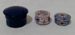 Lote contendo 3 caixinhas em porcelana, sendo, 1 francesa Saint Daflour na tonalidade azul cobalto (altura 5 cm e diâmetro 8 cm), 1 com tom prevalecente rosa (altura 3,5 cm) e 1 com tom prevalecente azul (altura 2,5 cm).