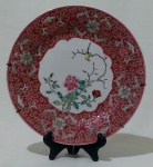 Prato decorativo chinês para parede, em porcelana na tonalidade branca, com desenho de fauna e flora no centro, borda na tonalidade vermelha e detalhes florais. Medida diâmetro 25 cm.