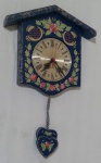 QUARTZ / LILY - Relógio em madeira, pintado a mão por Lily, na tonalidade azul com decoração floral e dourada, com pêndulo em formato de corações e máquina Quartz, à pilha, não testado. Medida altura com pêndulo 51 cm, largura 32 cm e profundidade 6 cm.