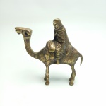 Escultura em bronze de um homem em cima de um camelo, vendida no estado conforme fotos. Mede 11 cm de altura.