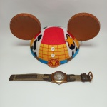 DISNEY - Lote com Chapéu da Disney em alusão ao 'Xerife Woody' do filme "Toy Story", e um relógio Disney Parks com imagem do Mickey funcionando sem garantias futuras. Mede 30 x 15 cm.