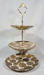 ruteira de 3 estágios em porcelana com flores em ouro sobre fundo branco e rosa. DImensões: 34cm alt; Diametros: 21, 16 e 13 cm.