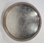 Bandeja redonda em metal espessurada a prata com fundo cinzelado com folhas e arabescos, borda fenestrada. Borda com desgaste no banho. Dimensões: 31x6 cm. (diâmetroxalt)