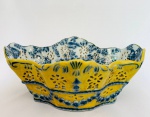 Floreira em porcelana com pintura à mão, nas cores amarelo e azul, com detalhes vazados e borda rendada. Med. 26x20 cm. Alt. 10 cm.