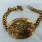 MILITARIA (R033) - ANTIGA PULSEIRA de uso da Força Aérea Brasileira - FAB ou da Aviação do Exército. Ostenta ao centro o Brasão de Armas da República, com asas laterais. Fabricada em metal. Apresenta desgastes em razão do uso e do tempo.
